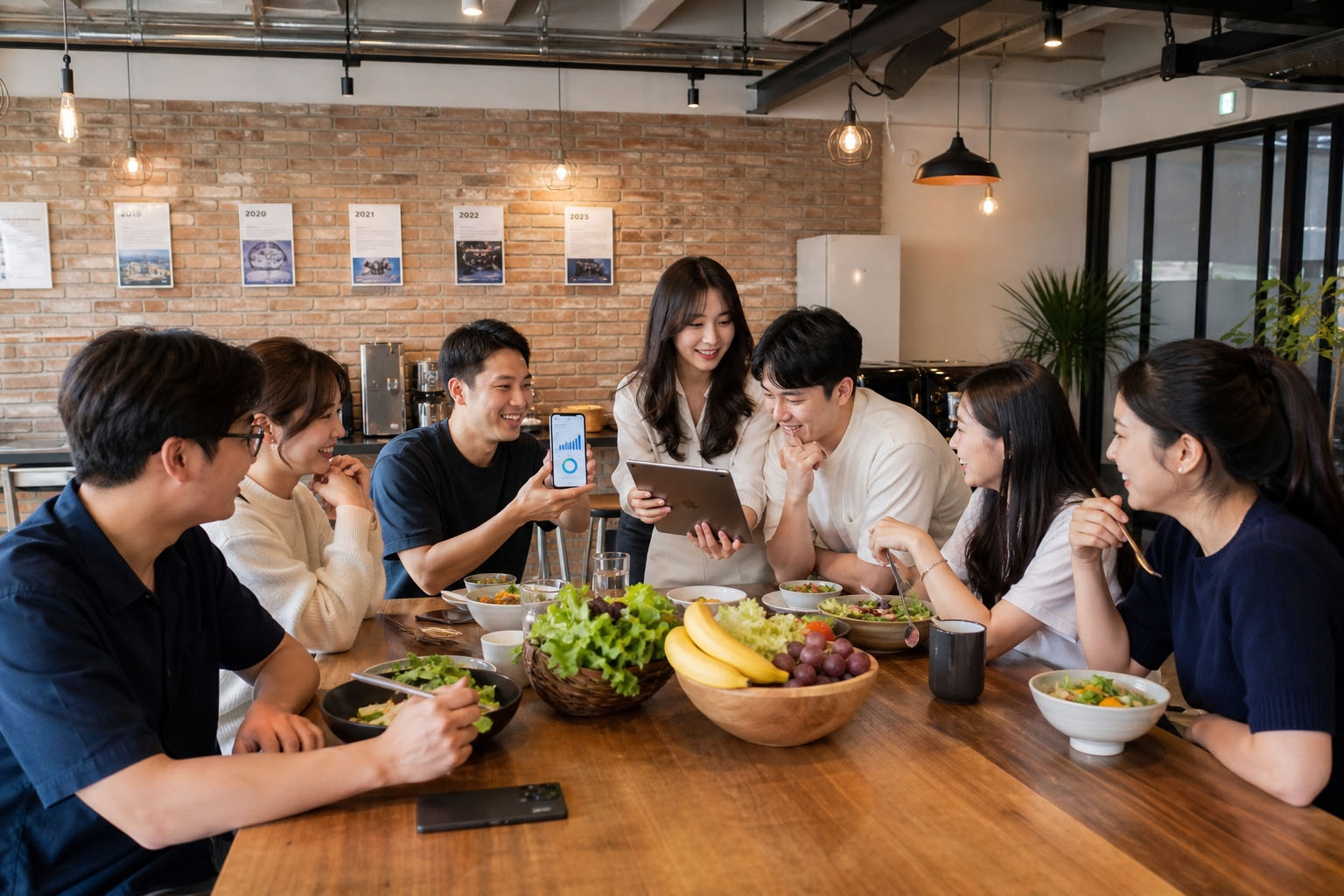 테이블에 둘러앉아 스마트폰·태블릿으로 매장 홍보 성과를 함께 확인하는 팀의 모습